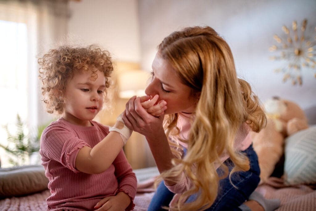 mom kissing her daughter's injured hand