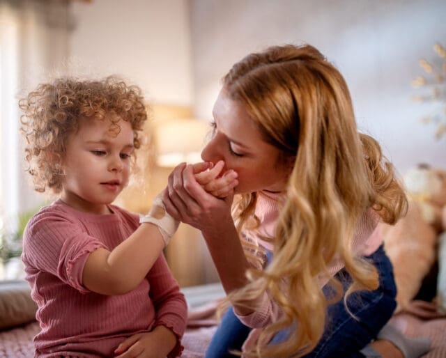 mom kissing her daughter's injured hand