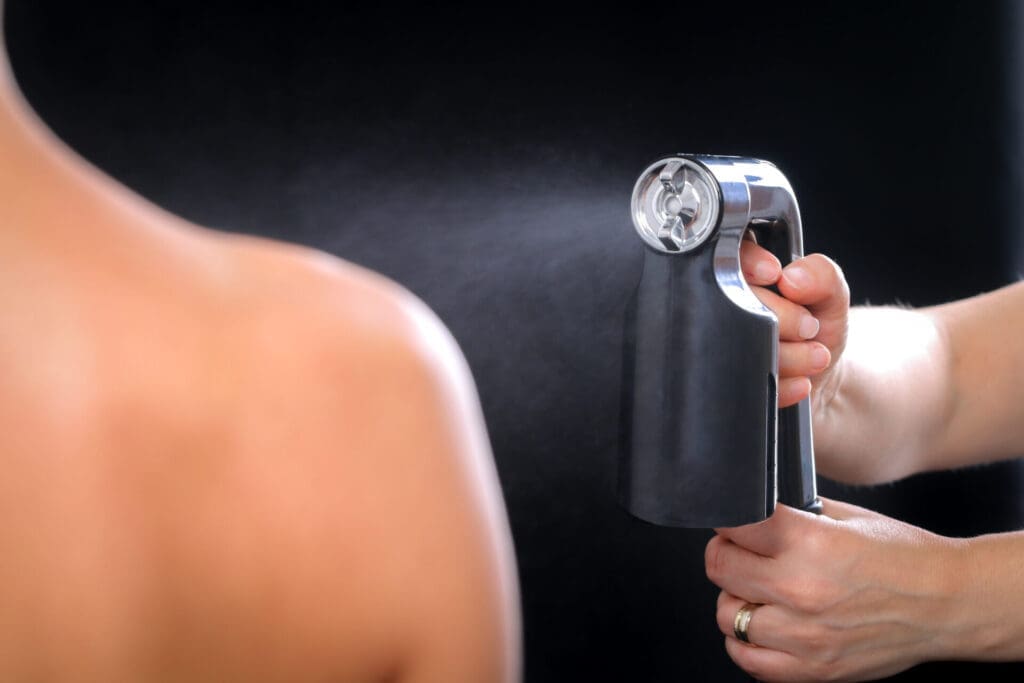 a spray tan being applied to a shoulder