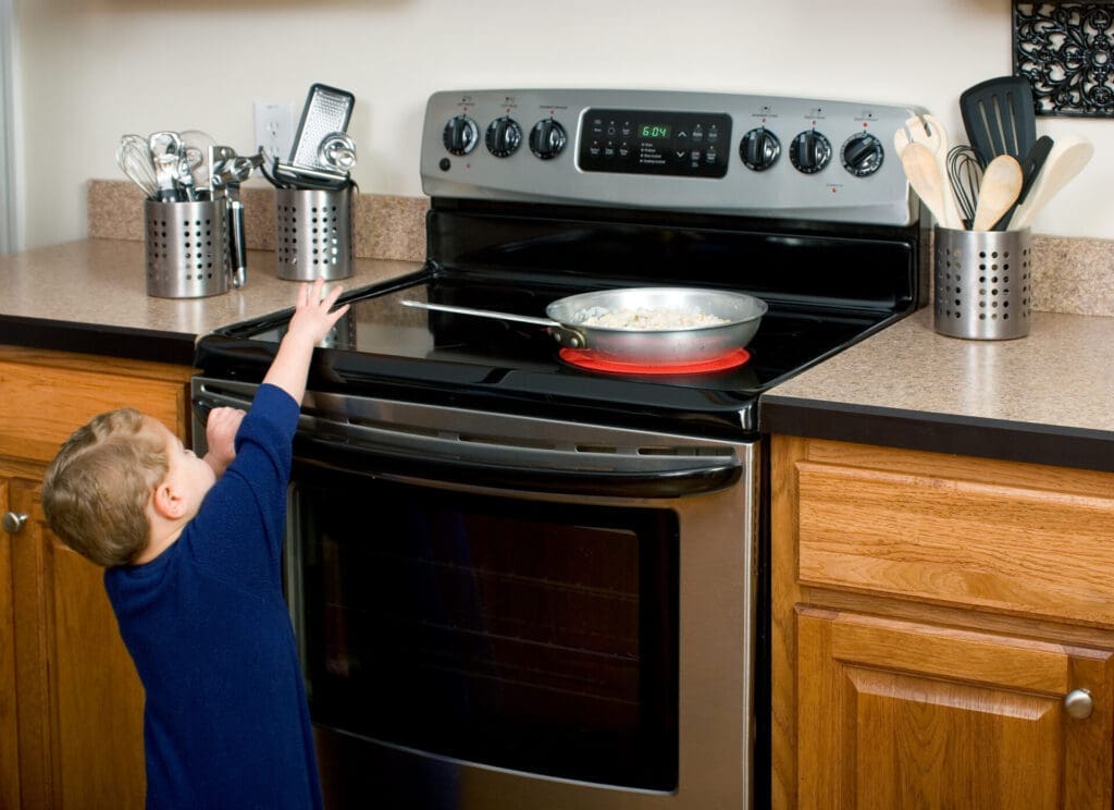 child reaching for hot pan on stove, at risk of burn