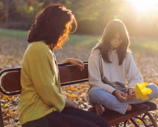 Mother and teenage daughter spending time together and mother advising her daughter who looks serious.