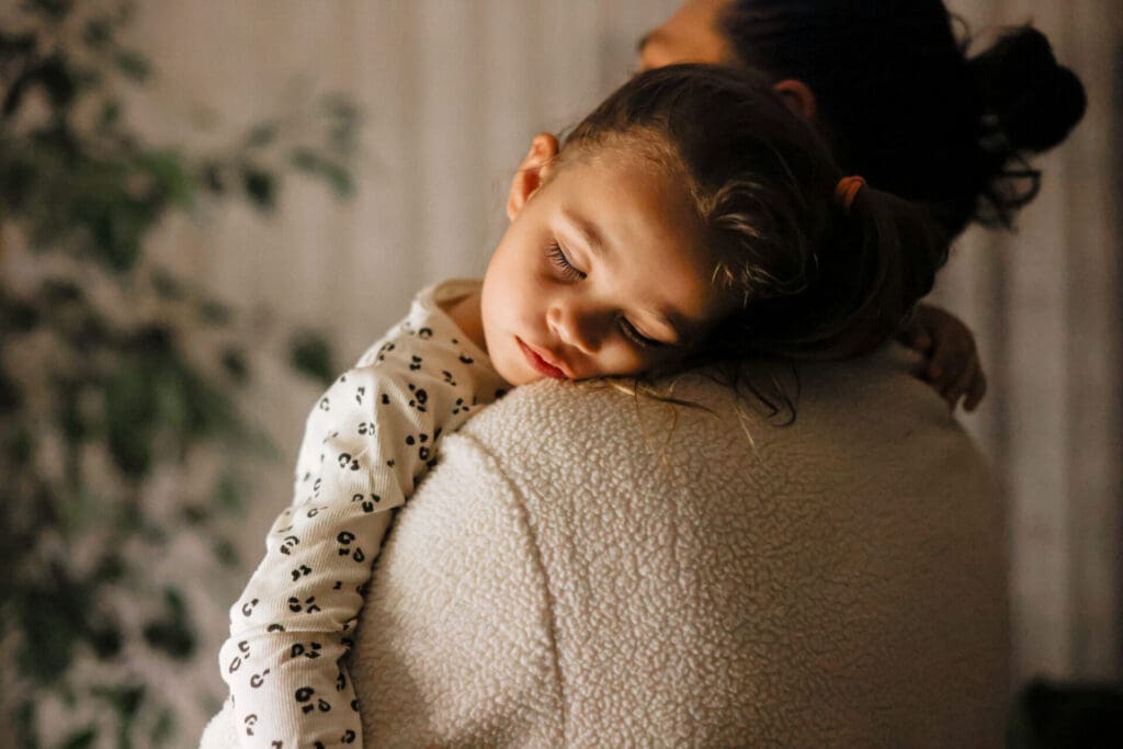 child asleep on parents shoulder while being held