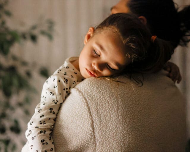 child asleep on parents shoulder while being held