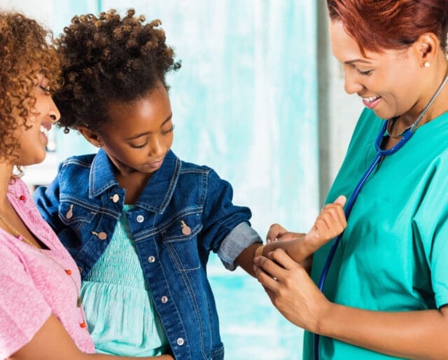 Doctor applying bandaid to arm of little girl after vaccinations
