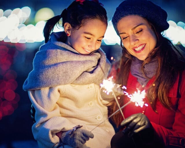 woman and child smiling at sparklers at New Years
