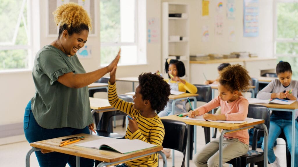 Teacher high fiving a student in a classroom