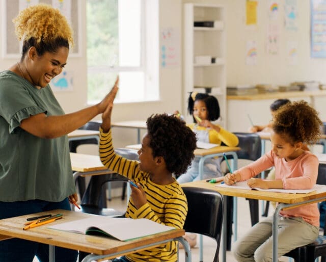 Teacher high fiving a student in a classroom