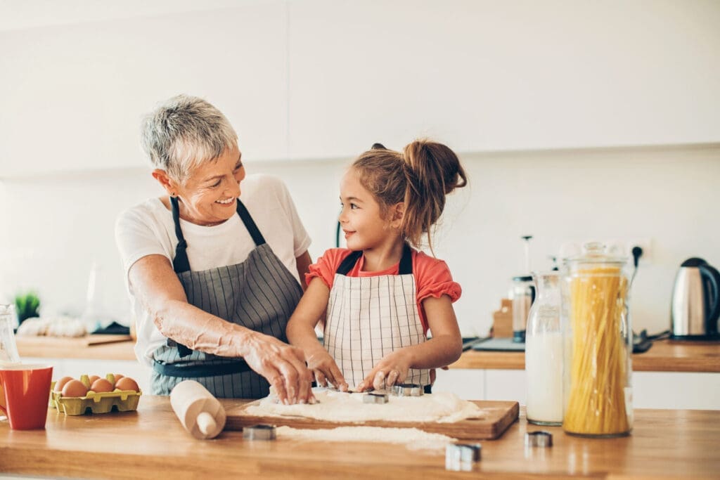 girl and grandma in the kitchen baking and laughing together