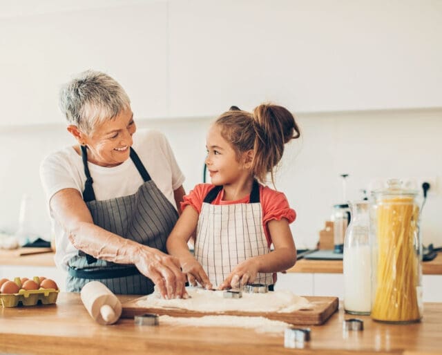 girl and grandma in the kitchen baking and laughing together