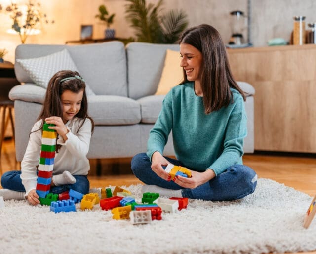 Mom and daughter sitting on the floor, playing with blocks
