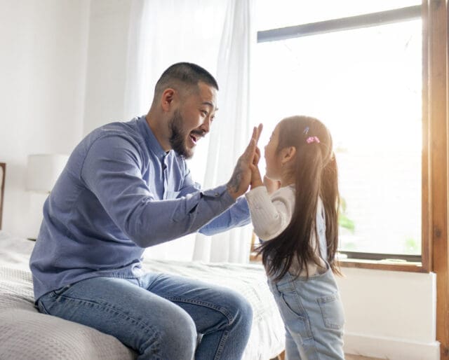 little asian girl play with dad hands and palms, korean child high five to father, happy asian family