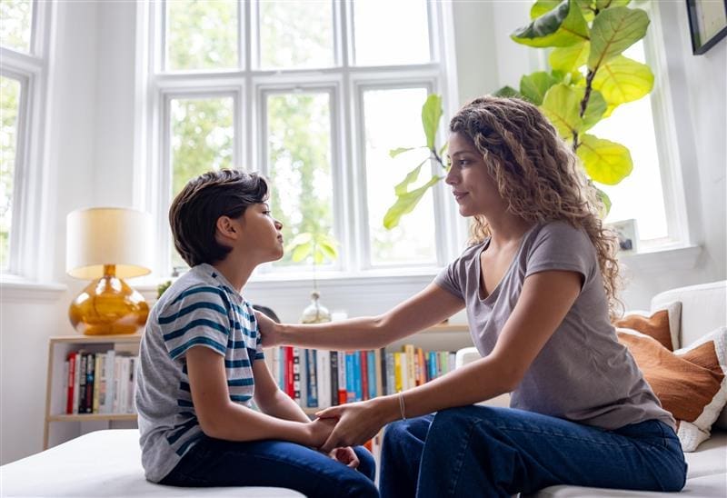 Mother and adolescent child sitting down and discussing how they feel