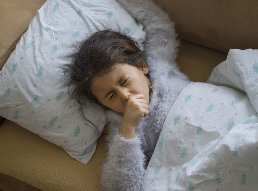 Little girl sick, coughing with her hand over her mouth