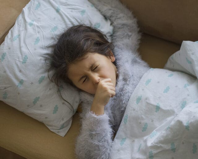 Little girl sick, coughing with her hand over her mouth