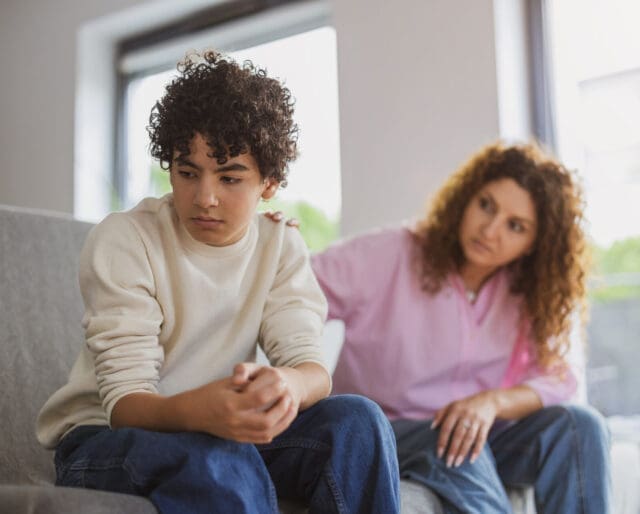 Mom comforting young child on a couch.