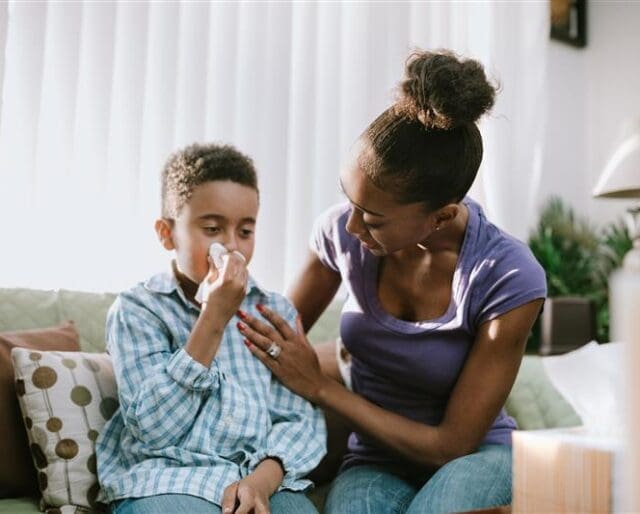 Image of a mother holding a tissue to her young son's nose