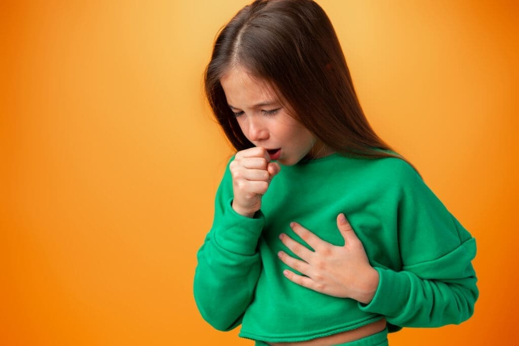 Teen girl wearing casual clothes feeling unwell and coughing against orange background
