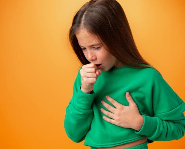 Teen girl wearing casual clothes feeling unwell and coughing against orange background