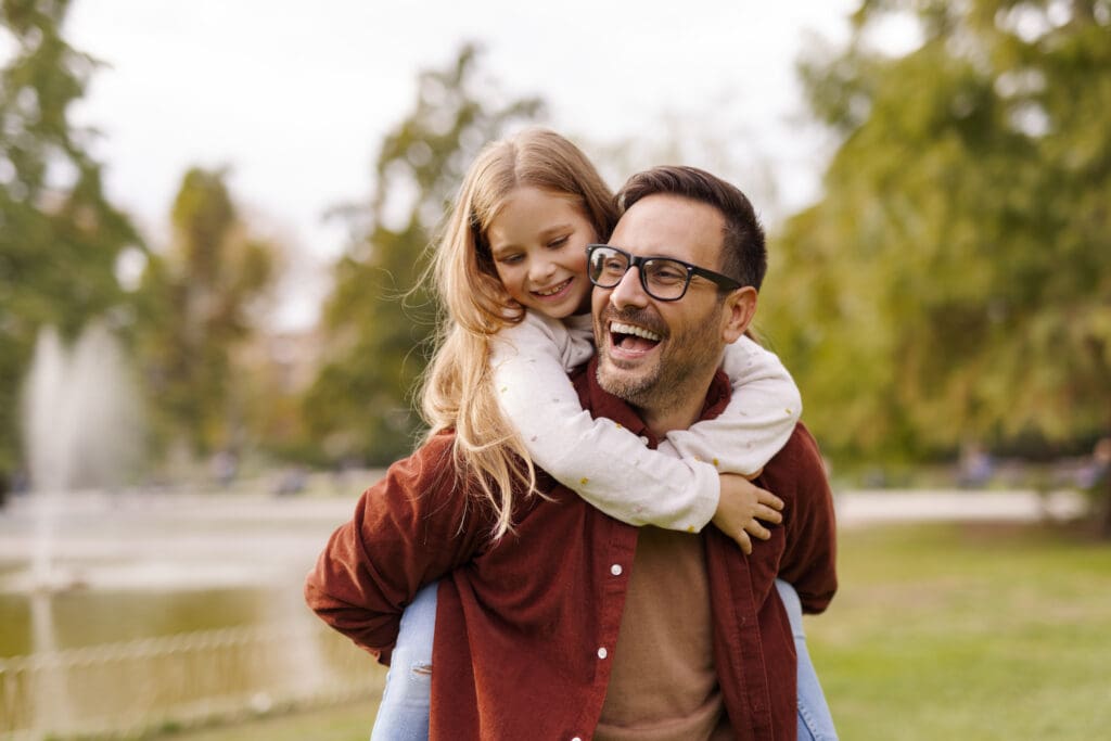 Man Carrying His Daughter on His Back Outdoors.