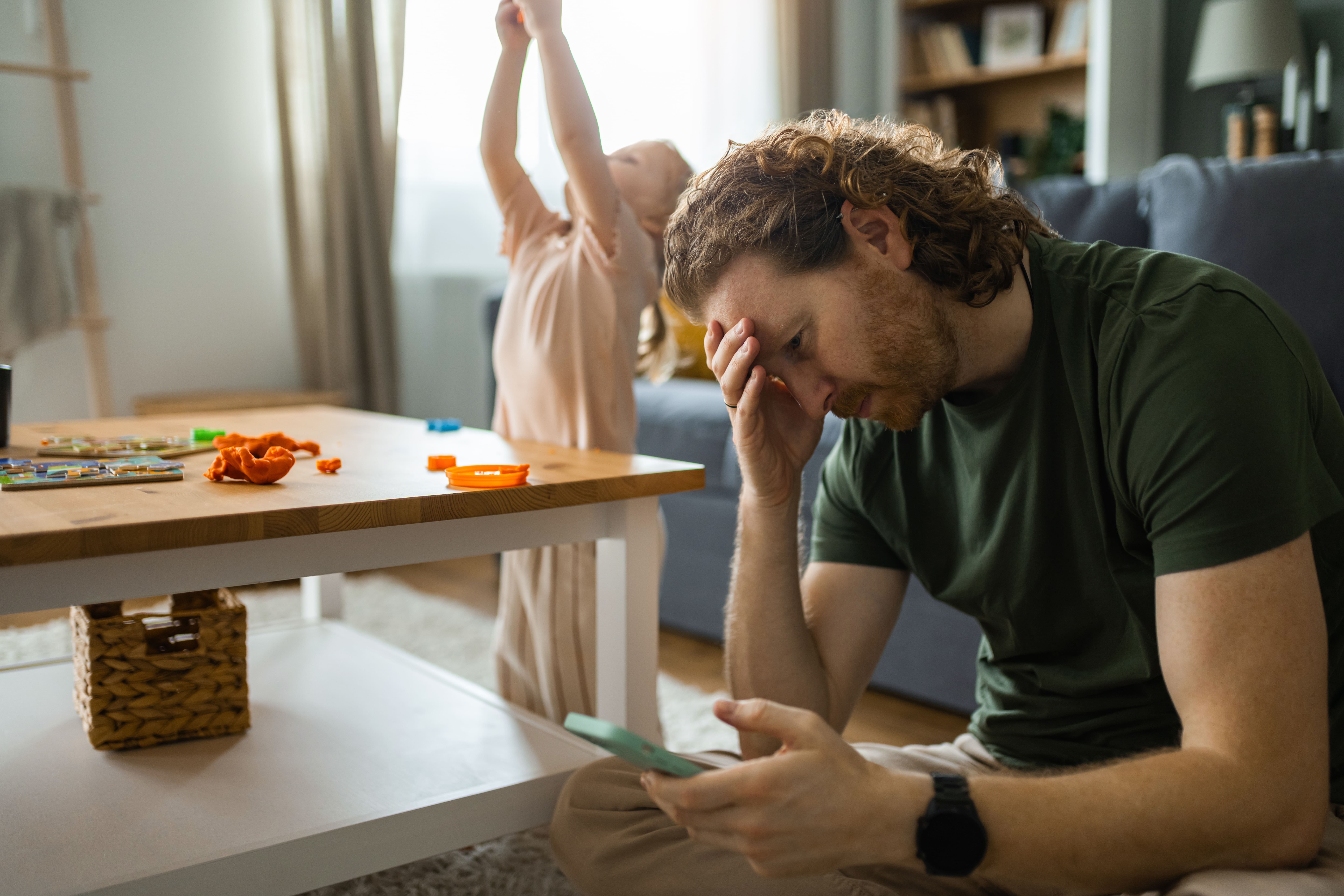 Stressed father experiencing parenting burnout in messy living room